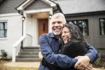 Young couple hugging in front of their new home.
